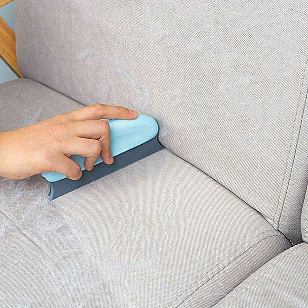 Handheld pet hair scraper brush pulling a pile of dog fur out of a carpet