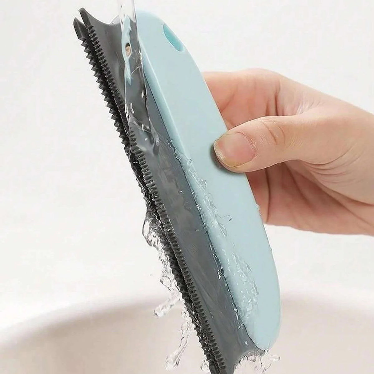 Handheld pet hair scraper brush pulling a pile of dog fur out of a carpet